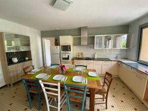 a kitchen with a wooden table and chairs in a room at Ma tonnelle fleurie in Beaumont-de-Lomagne
