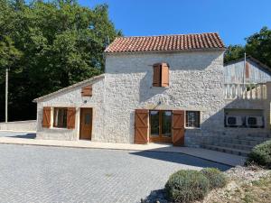 a stone house with wooden doors on a driveway at Les Lavandes in Tréjouls