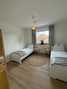 two beds in a room with a window at Ildiz Ferienwohnungen in Wiefelstede
