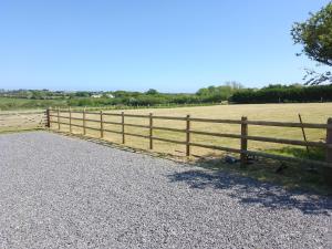 a wooden fence next to a field with a horse at Southview Wild Camping in Haverfordwest