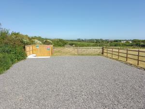 a gravel driveway with a gate and a fence at Southview Wild Camping in Haverfordwest