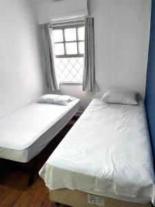 3 quartos a 400m do metro Ana Rosa في ساو باولو: سريرين في غرفة بها نافذة +صورتان