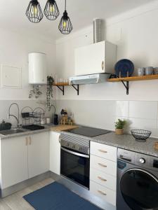 a kitchen with white cabinets and a stove top oven at Refúgio do Bugalho - Casa da Oliveira in Alandroal