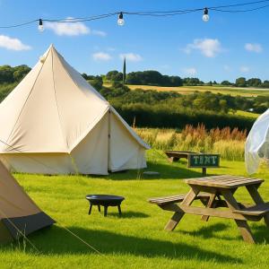 a tent and a picnic table in a field at Huge Cozy Bell Tent with Tv and Heating in Llanfairpwllgwyngyll