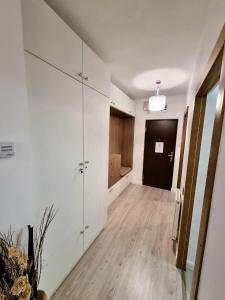 a living room with white cabinets and a hallway at Ra Apartment in Oradea +2 photos