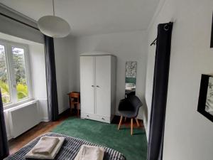 Un dormitorio con una cama, un armario y una silla. en T2 cozy avec vue sur Morlaix, en Morlaix