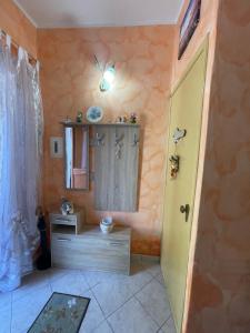 a bathroom with a yellow door and a mirror at Sweet Home Rosy in Calatabiano