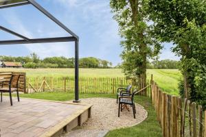 a patio with chairs and a wooden fence at See and Stay Oostkapelle - Dog-Friendly Holiday Home in Oostkapelle