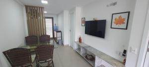 un soggiorno con tavolo e TV a parete di The Home São Miguel do Gostoso Apt 006 a São Miguel do Gostoso