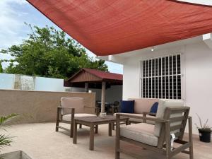 a patio with chairs and a table and a red roof at Villa Catalina Beach House in Punta Santiago