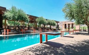 a swimming pool with tables and trees in front of a building at Ikaros Suites in Amoudara Herakliou