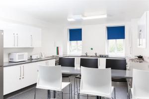 a kitchen with white cabinets and white chairs at Alexander Fleming House, London in London