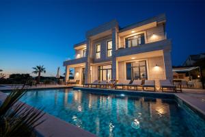 a large house with a swimming pool in front of it at Villa Stone house in Novalja