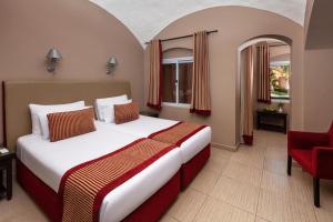 Una habitación de hotel con una cama y una silla roja. en JAZ Makadi Oasis Resort, en Hurghada