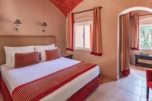 1 dormitorio con 1 cama con cortinas rojas y ventana en JAZ Makadi Oasis Resort, en Hurghada