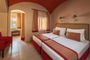 Un dormitorio con una cama grande y una silla roja. en JAZ Makadi Oasis Resort, en Hurghada