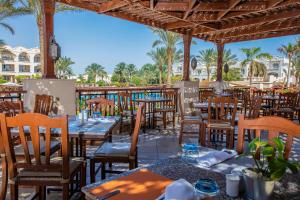 an outdoor restaurant with tables and chairs and palm trees at JAZ Makadi Star & Spa - Adults Only in Hurghada
