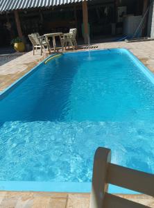 a blue swimming pool with a table and chairs at Pousada Rota in Paty do Alferes