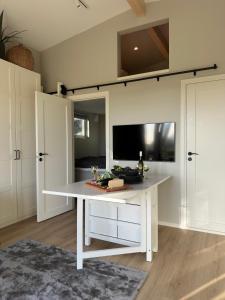 a dining room with a white table and a tv at Skrylle Hideaway - cozy tiny house near Lund in Dalby +19 photos