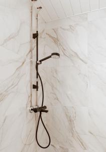 a shower with a black shower head on a white wall at Uniikki keskustahuoneisto pihaterassilla, bm Garden Apartments no1, free parking in Lahti +26 photos