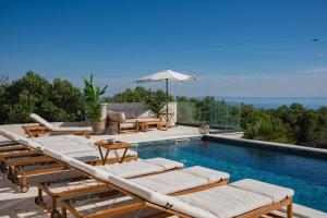 a swimming pool with lounge chairs and an umbrella at Villa Stone house in Novalja