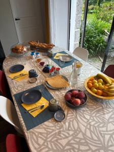 a table with plates of food and fruit on it at Chambres Kergana in Landéda