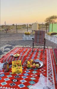 a table with a plate of fruit on a blanket at Jabreen Castle Camp in Naţţālah