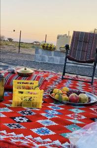 a blanket with a plate of fruit on a table at Jabreen Castle Camp in Naţţālah