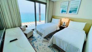 a hotel room with two beds and a view of the ocean at شقه فاخره في فندق العنوان ثلاث غرف نوم اطلاله علي البحر مباشره in Fujairah +14 photos