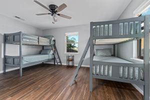two bunk beds in a room with a ceiling fan at Walnut House - Close to Downtown Fire Pit in Fredericksburg