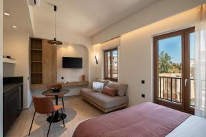 a bedroom with a bed and a couch and a tv at Zoera Suites by Ethos in Chania