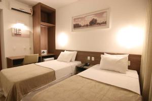 利尼亚雷斯Quarto duplo Samba Hotel Linhres的有两张床和一张书桌的酒店房间