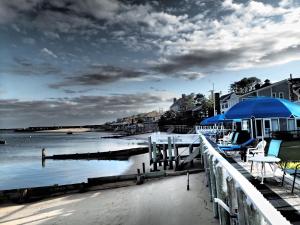 een steiger met stoelen en een parasol naast het water bij The Masthead Resort in Provincetown