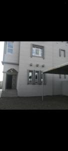 a white building with a door and windows at فيلا في صحم in Murtafa‘āt Şaḩam