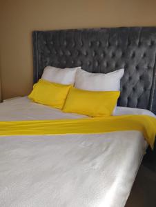 a bed with two yellow pillows on top of it at Ivy Cottage in Harare