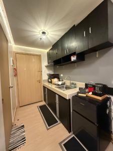 a small kitchen with black cabinets and a sink at Condo in Fairview SM Terraces Cozy Netflix in Manila +1 photo