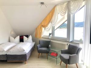 a bed and two chairs in a room with windows at Sunside Ferien Wellness Oase Hotel Apartment's Schwarzwald am Schluchsee in Schluchsee +33 photos