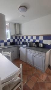 a kitchen with white cabinets and blue and white tiles at petit esperantza in Saint-Pée-sur-Nivelle