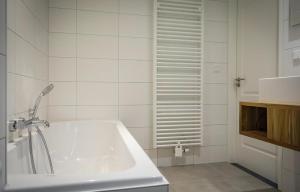 a white tub in a bathroom with white tiles at G-21A Bouwlust in De Cocksdorp +16 photos