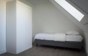 a bedroom with a bed with white walls and a skylight at G-21A Bouwlust in De Cocksdorp
