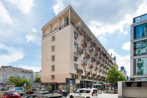 a tall building with cars parked in a parking lot at Widok Warsaw City Apartment by BookingHost in Warsaw