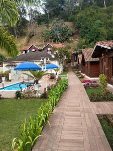a walkway leading to a resort with a pool and umbrellas at Pousada Mon Desir in Penedo