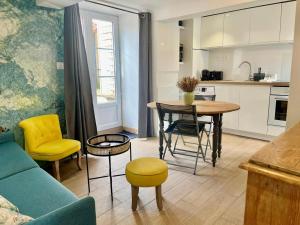 a kitchen and a living room with a table and chairs at Petite vague - maison atypique avec terrasse in Saint-Aubin-sur-Mer