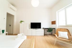 a white room with a bed and a desk and a tv at Alberto's Suites Piazza Roma in Oristano +13 photos