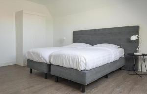 a bedroom with a large bed with white sheets at G-21 Bouwlust in De Cocksdorp