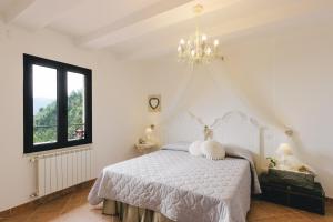 a bedroom with a white bed and a chandelier at Il Cuore delle Apuane in Antona +23 photos