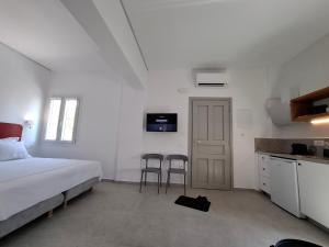 a bedroom with a bed and a kitchen with two chairs at Gazìa in Mýkonos City
