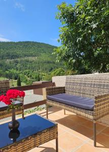 Un patio con dos sillas de mimbre y una mesa con flores rojas. en Casa De Férias, en Volvent