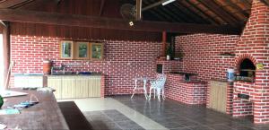 a red brick kitchen with a counter and a table at Chácara dos Azevedo in Divinópolis