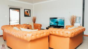 two orange leather couches in a living room with a tv at Kwagae farm in Kuruman